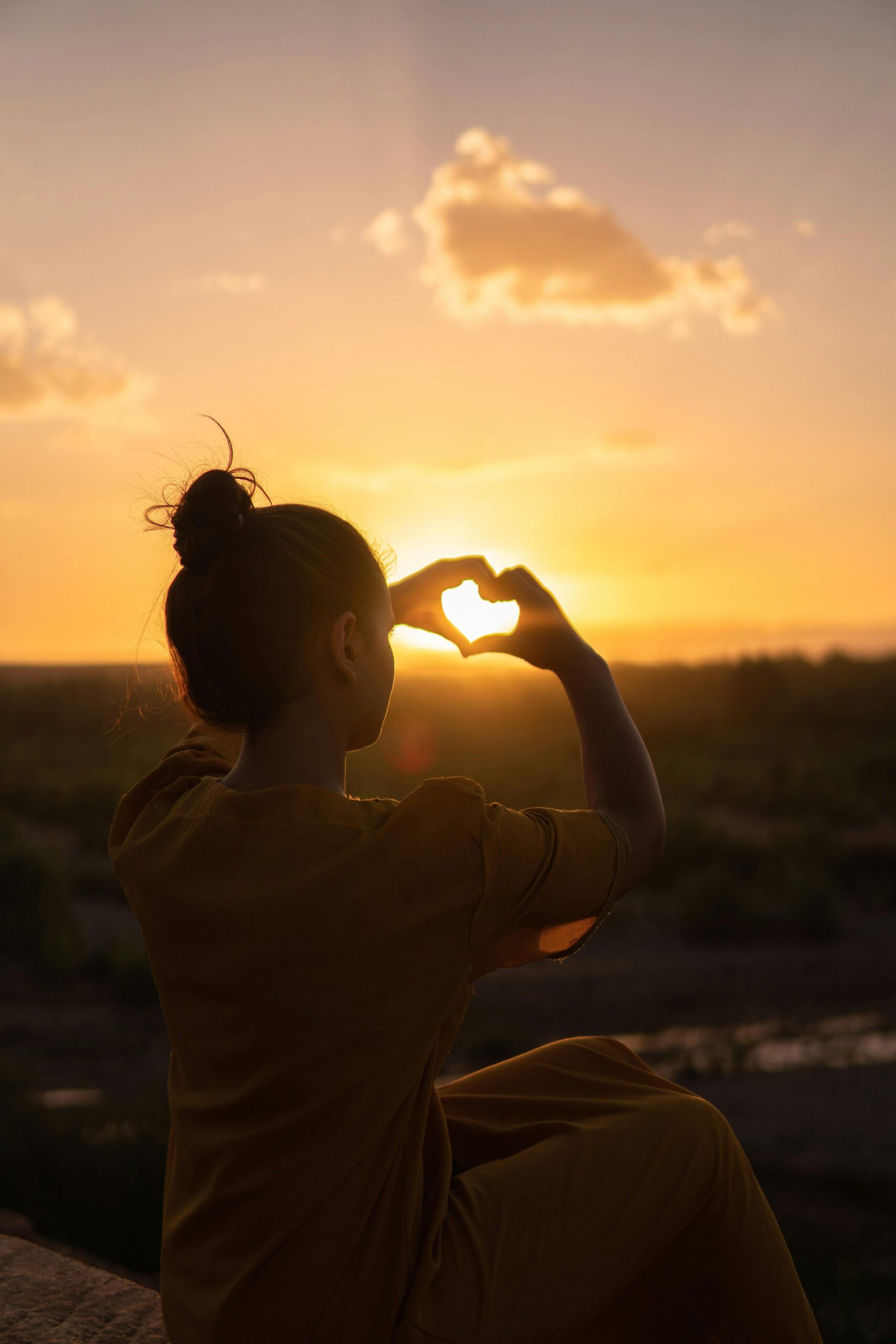 Vrouw maakt hartvorm bij zonsondergang
